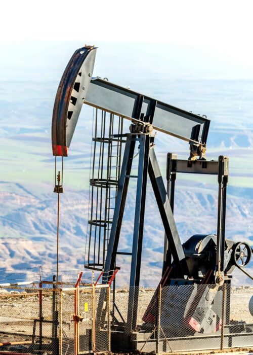 A pumpjack in the oil well. A pumpjack converts the rotary motion of the motor to a vertical reciprocating motion to drive the pump shaft, which is exhibited in the characteristic nodding motion.